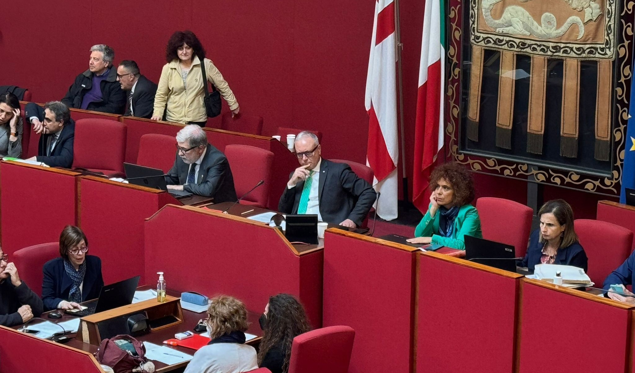 Il sindaco e presidente Marco Bucci Persone sedute in un'aula rossa