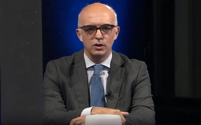 Un uomo con gli occhiali e la cravatta in uno studio televisivo