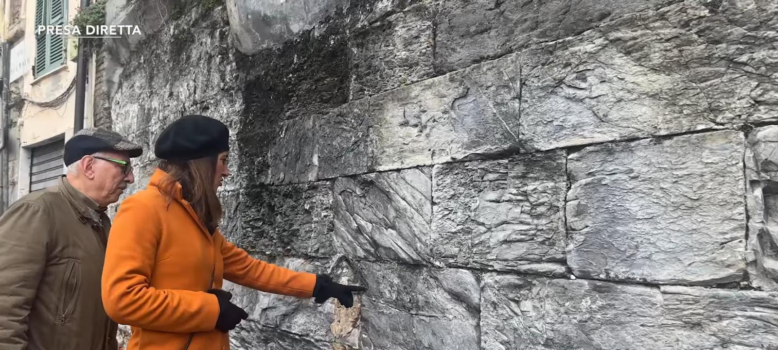 Una casa di pietra e due persone che indicano il muro