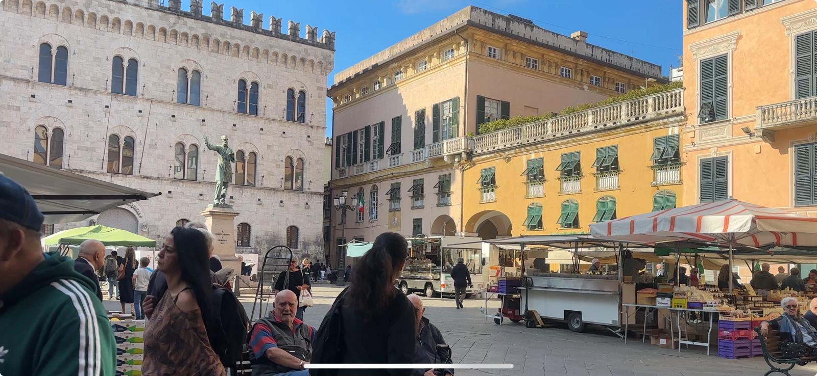 Una piazza con delle case e gente al mercato 