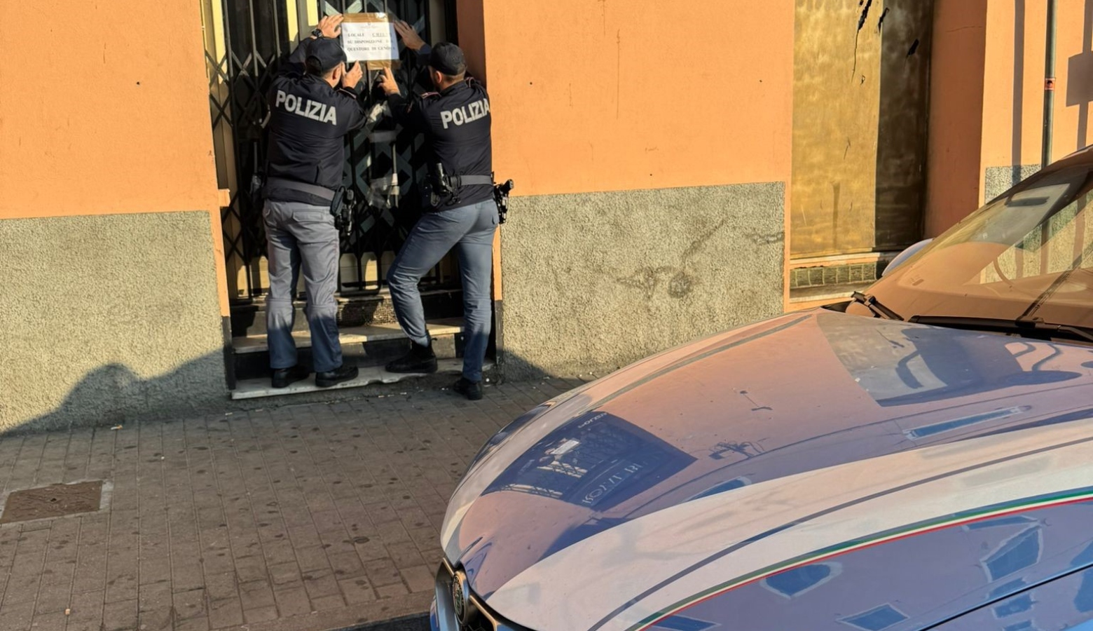 Due poliziotti mettono sigilli alla porta di un locale