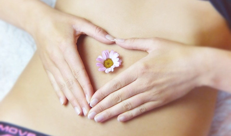 Una margherita appoggiata sull'ombelico di una donna