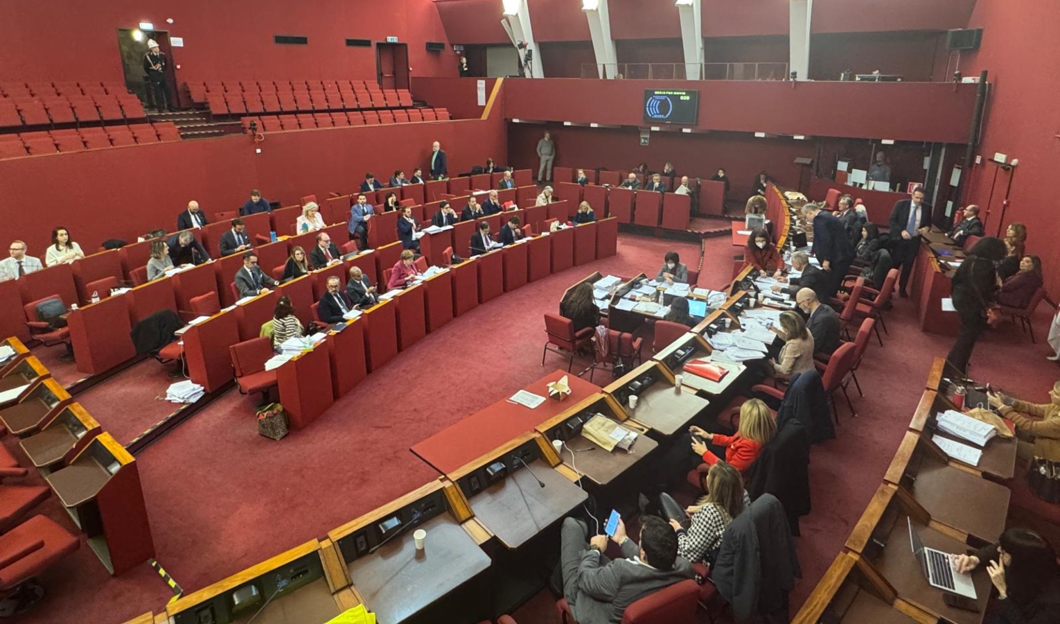 Aula rossa consiglio comunale di Genova Persone in piedi e seduti in una stanza chiusa tappezzata di rosso