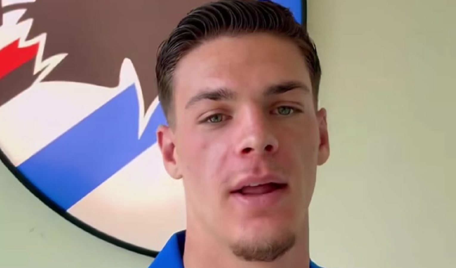 Un ragazzo in primo piano, alle spalle il logo della Sampdoria