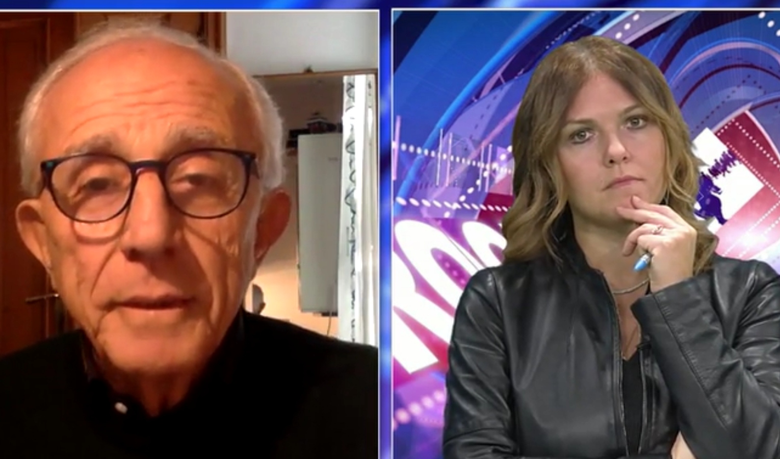 Un signore con gli occhiali in uno studio televisivo intervistato da una giornalista