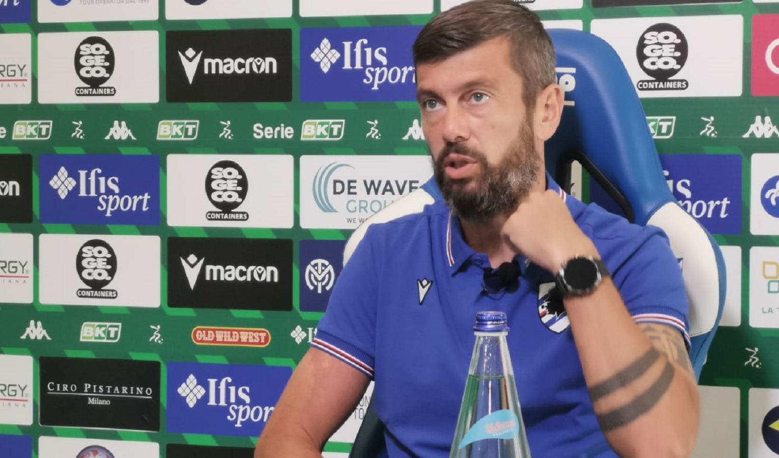 Un uomo seduto, con la barba, capelli neri e maglia della Sampdoria. Davanti a lui una bottiglia d'acqua.