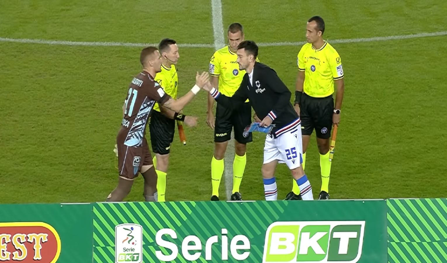 Due calciatori si salutano sotto gli occhi di tre arbitri