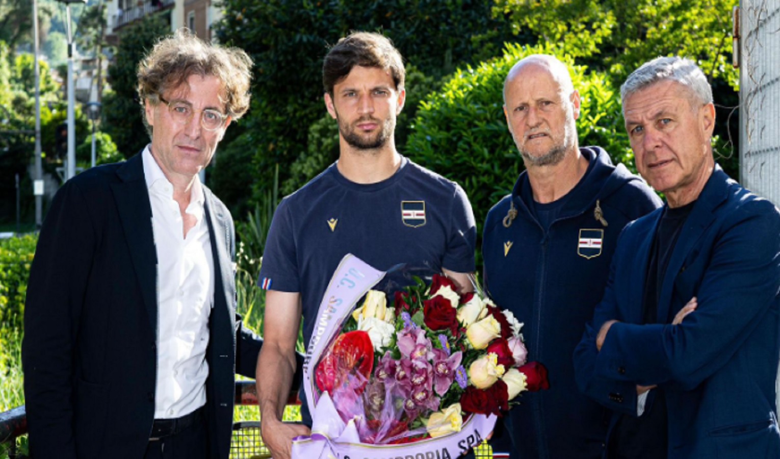 Quattro persone con un mazzo di fiori, sguardo serio