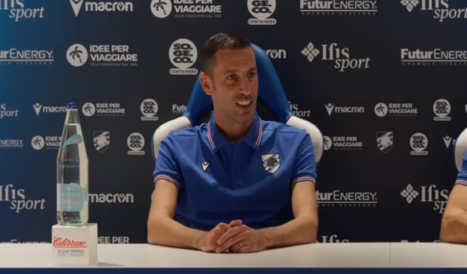 Un uomo seduto indossa una maglia polo della Sampdoria