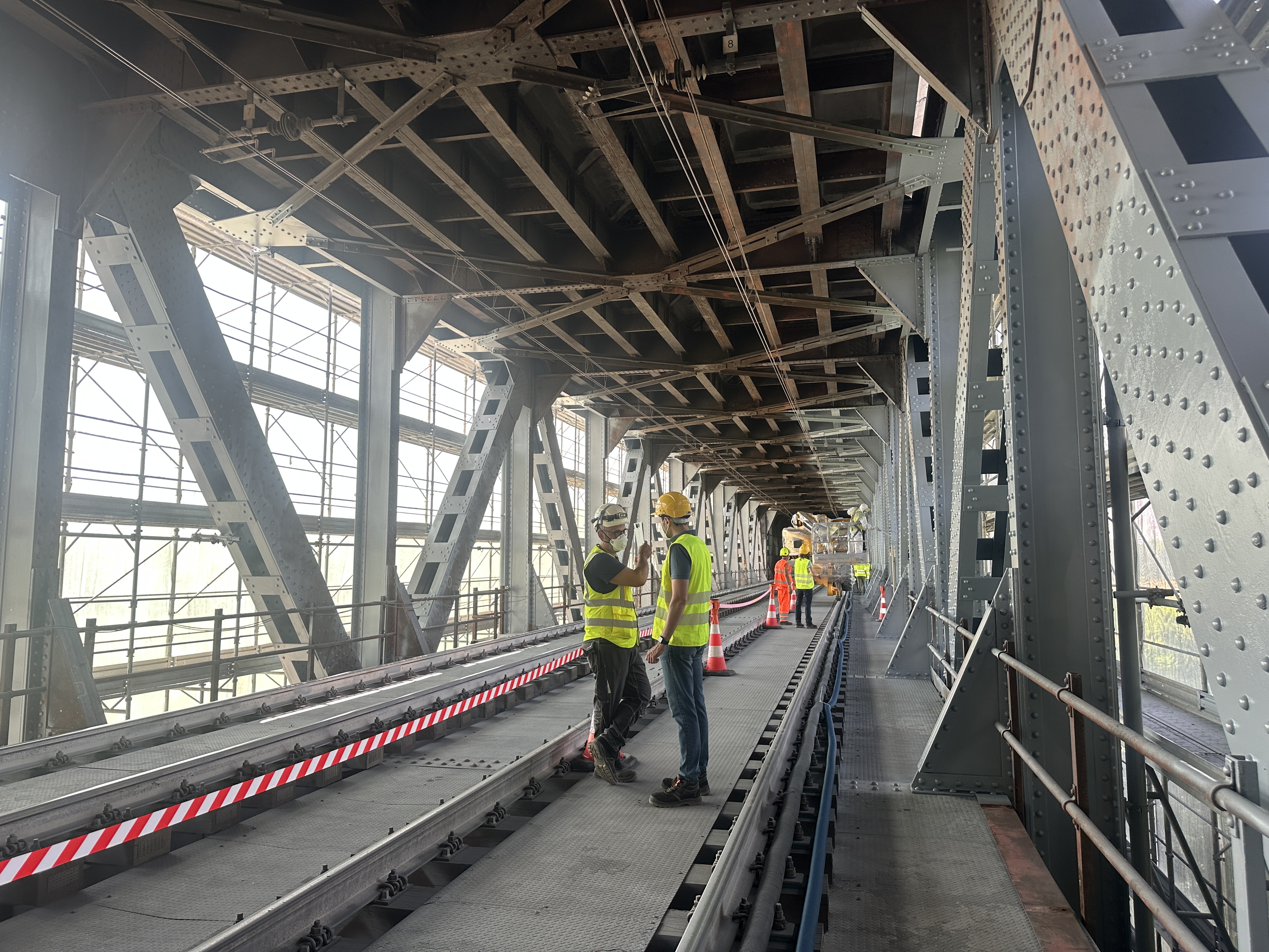 I lavori sul ponte sul Po a Pavia Uomini con pettorine gialle e caschi in un cantiere