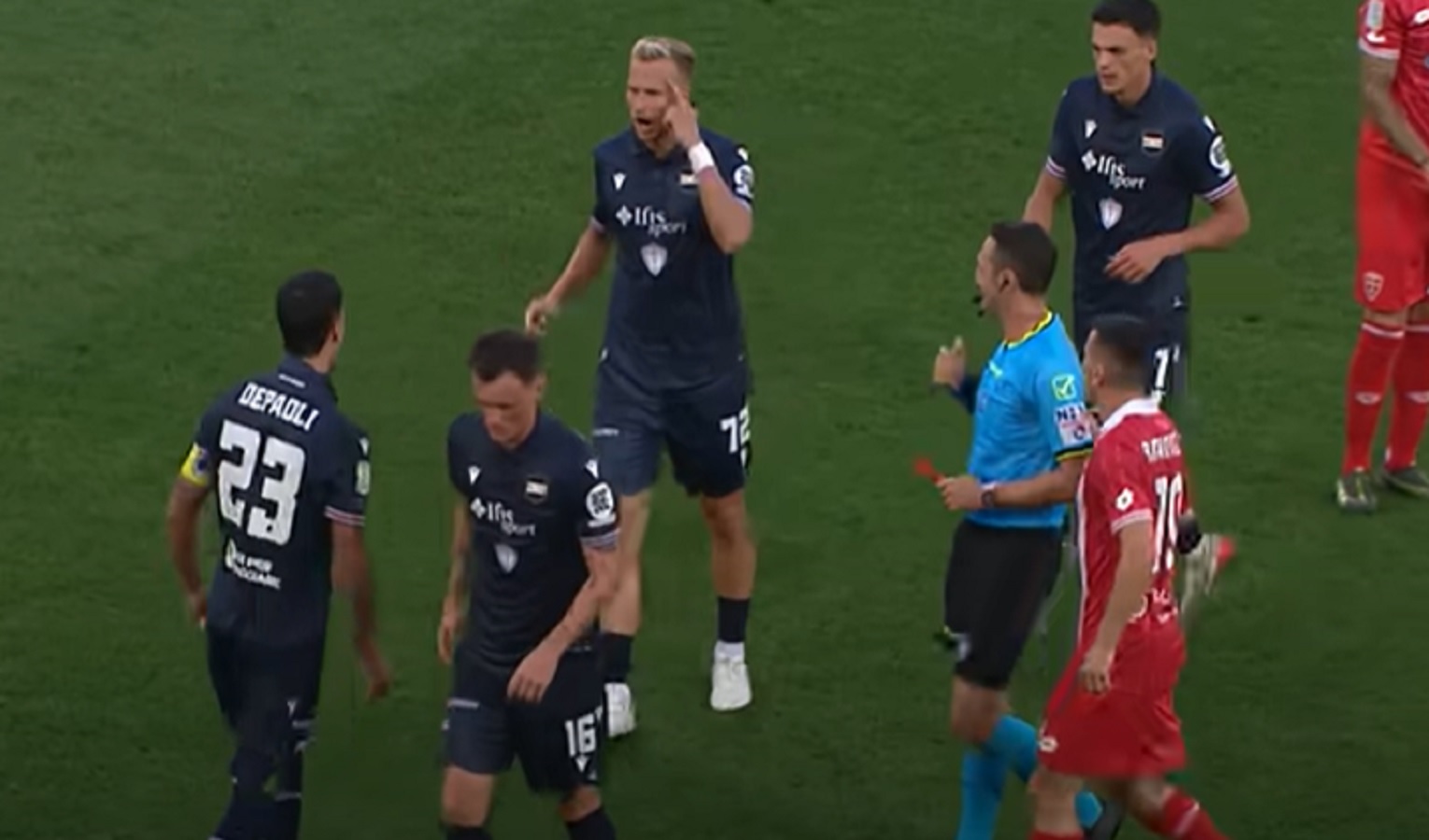 Calciatori in campo a gioco fermo, discussione in corso e si vede l'arbitro