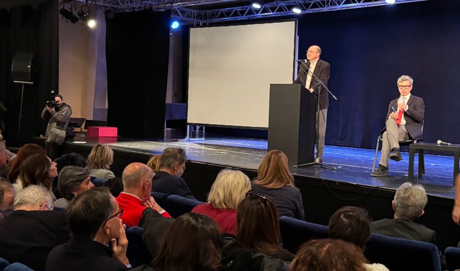 Il consigliere regionale del Partito Democratico Andrea Orlando Una sala di un teatro con due persone sul palco, una in piedi e l'altra seduta