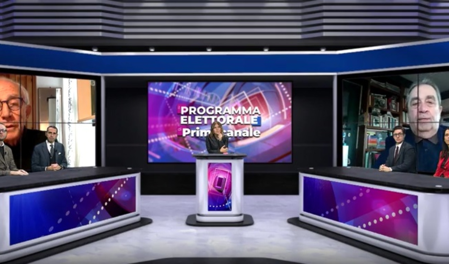 Uno studio televisivo con persone in piedi, sedute e collegate da remoto