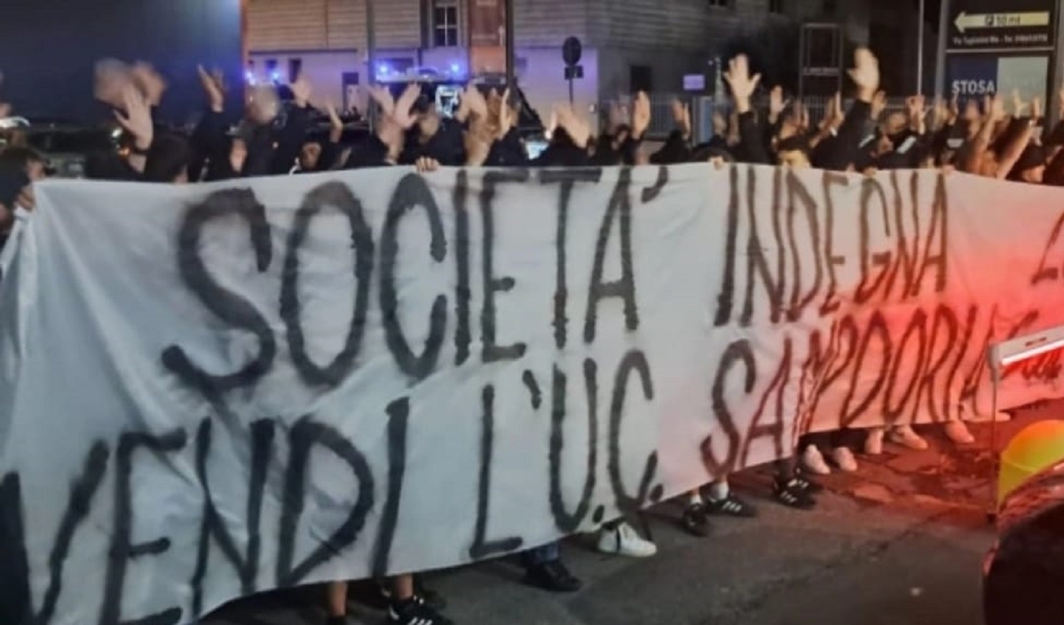 Uno striscione di contestazione, un corteo di persone