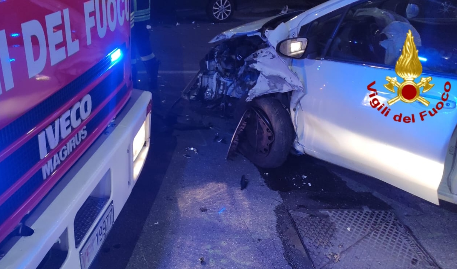 Il camion dei vigili del fuoco e un'auto semi distrutta