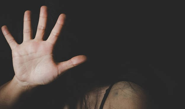 Una donna si difende da una violenza coprendosi il volto 