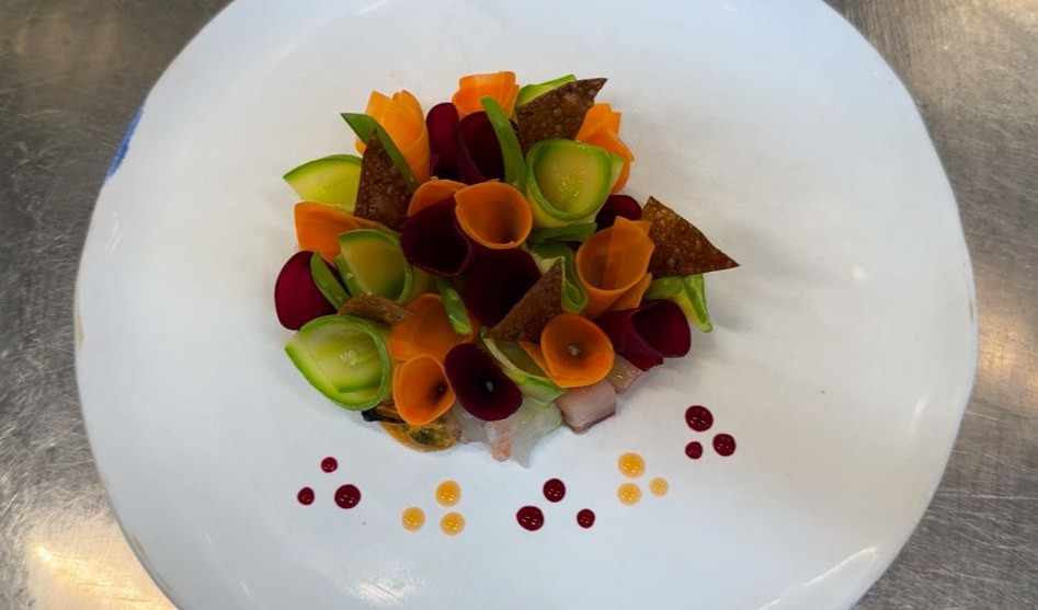 Il cappon magro rivisitato dello chef stellato Carote e zucchine arrotolate appoggiate su un piatto bianco